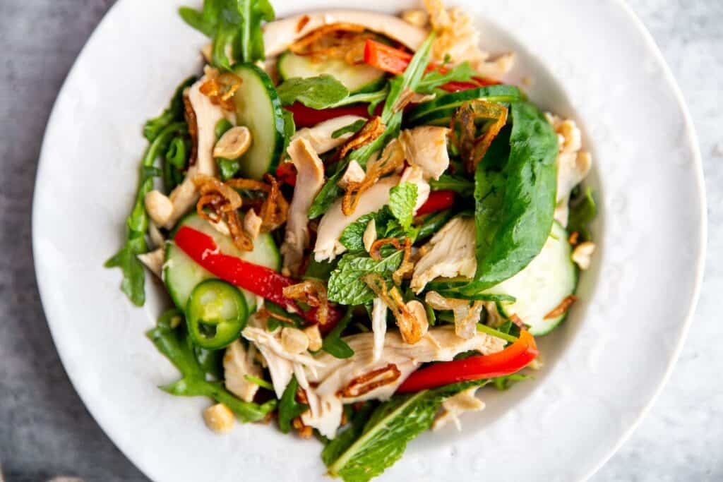 Chicken and herb salad tossed with chili lime dressing, served in a white bowl