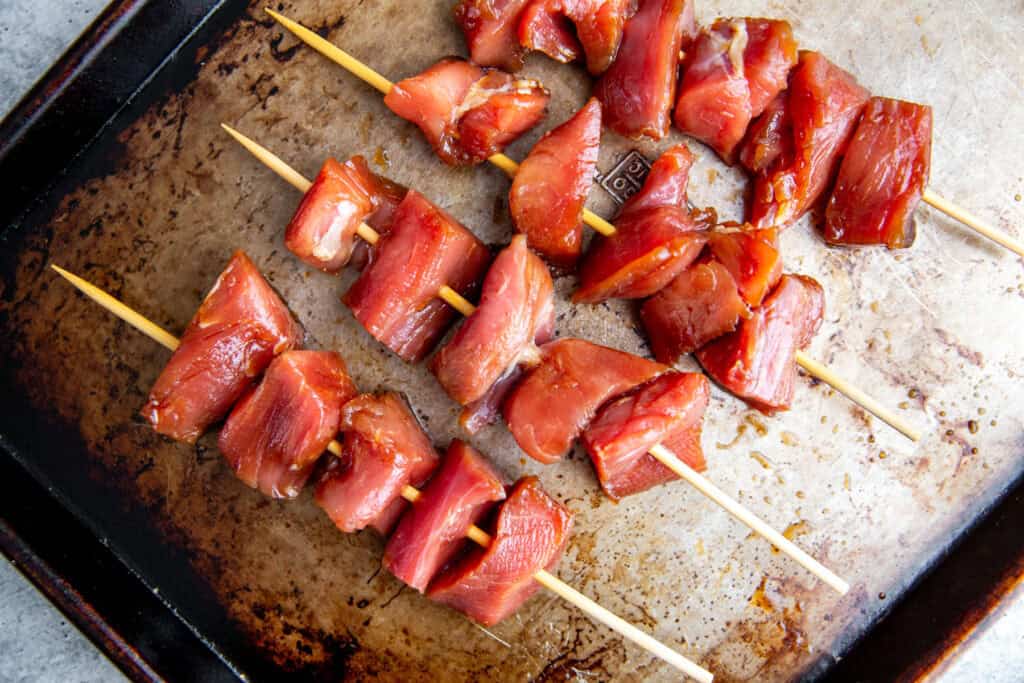 Raw marinated pork threaded onto skewers, ready for grilling
