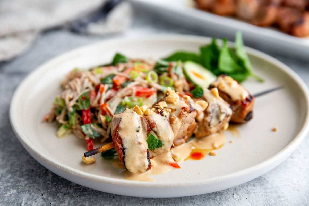 Grilled pork kebabs served over peanut noodle salad with fresh herbs and peanut dressing