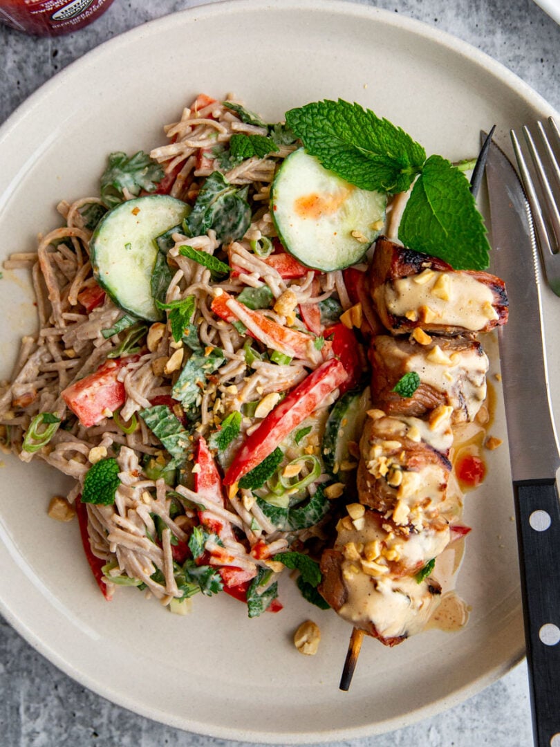 Grilled pork kebabs served over peanut noodle salad with fresh herbs
