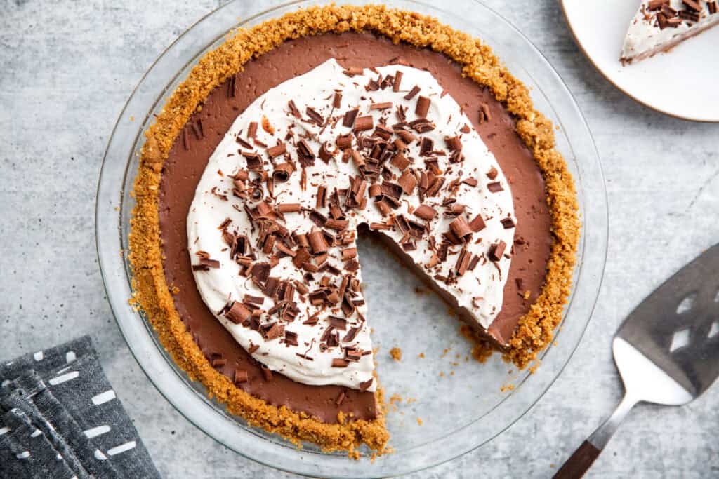 chocolate pudding pie in a glass pie plate with a slice taken out.