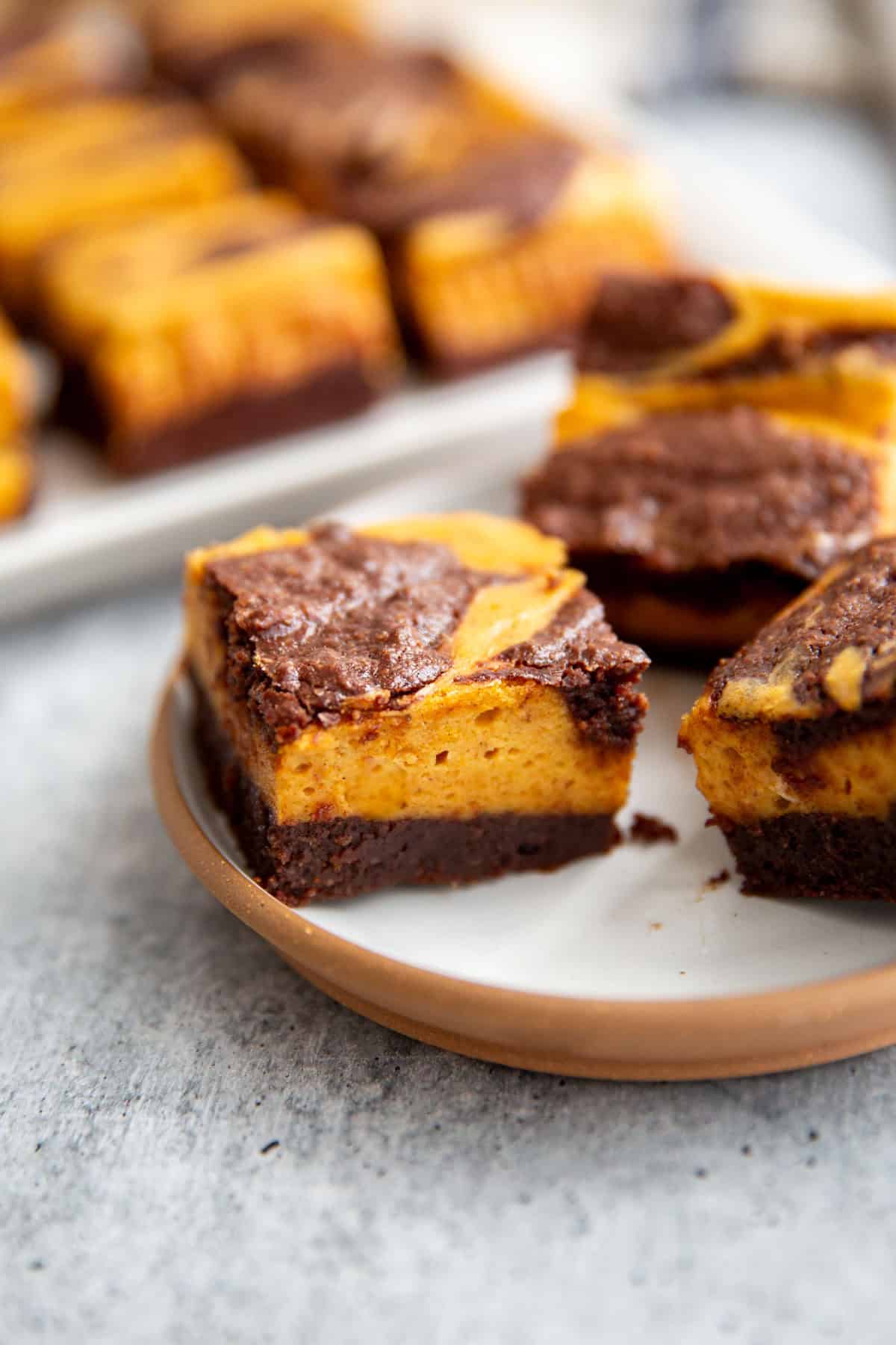 a close up photo of pumpkin cheesecake brownies on a pan