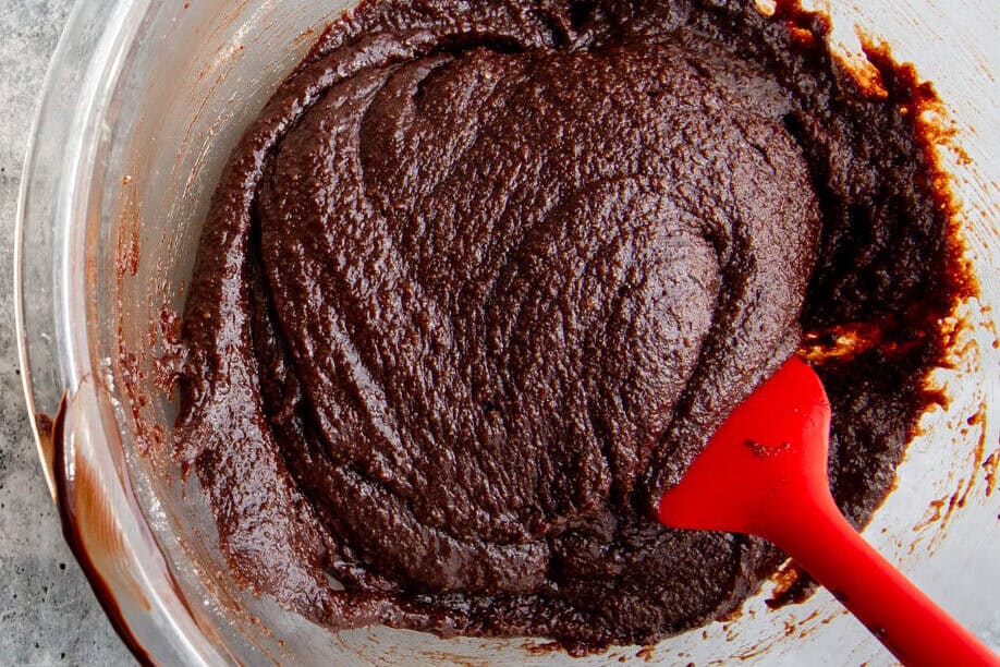 brownie batter mixed in a glass bowl with a red spatula