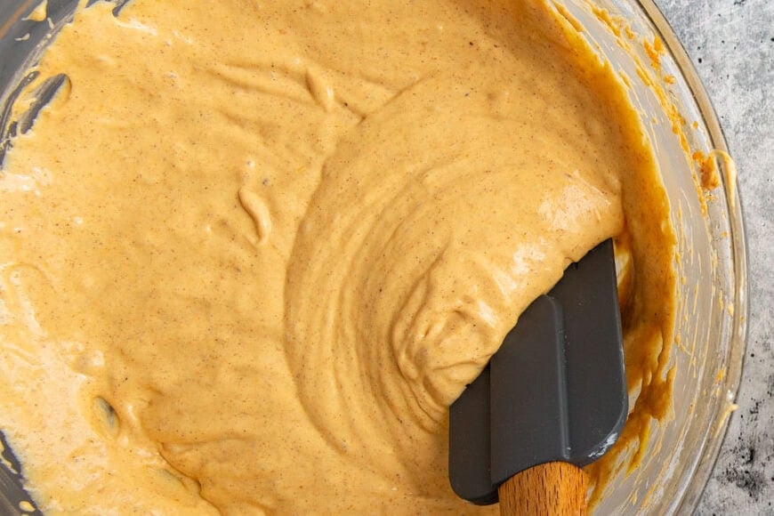 cheesecake batter in a glass bowl with a spatula