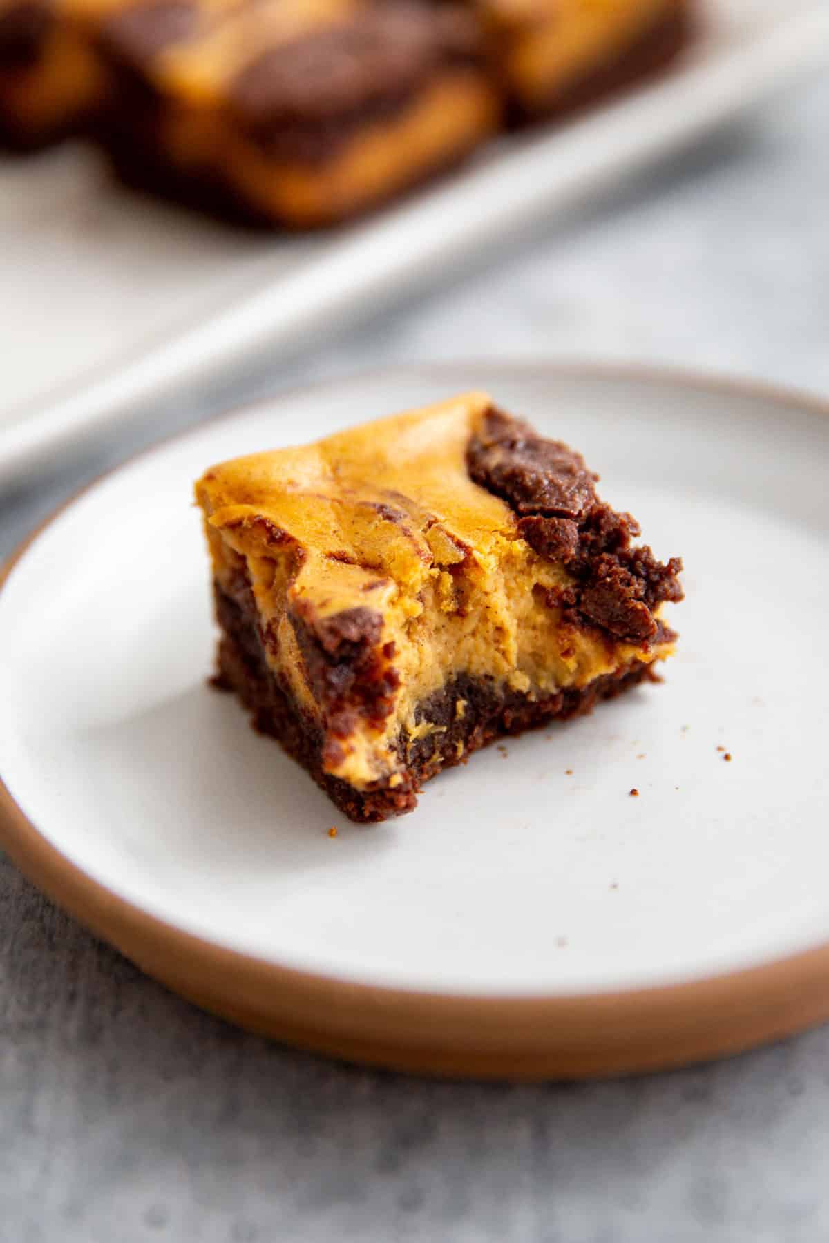 a bite taken out of fudgy pumpkin brownies swirled with cheesecake