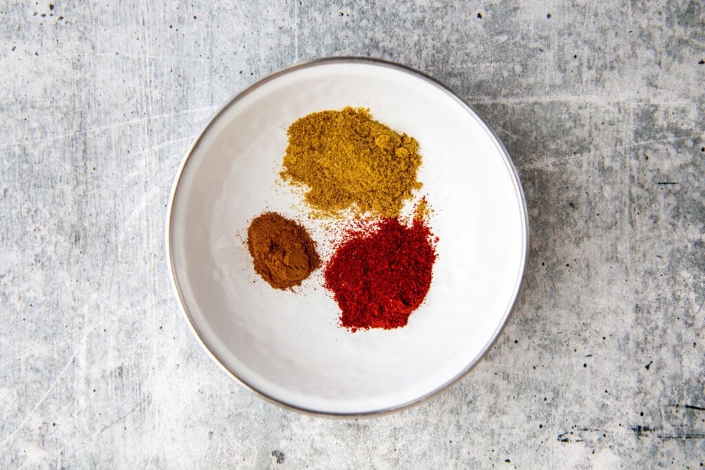 spices measured into a white bowl for the sweet potato peanut stew