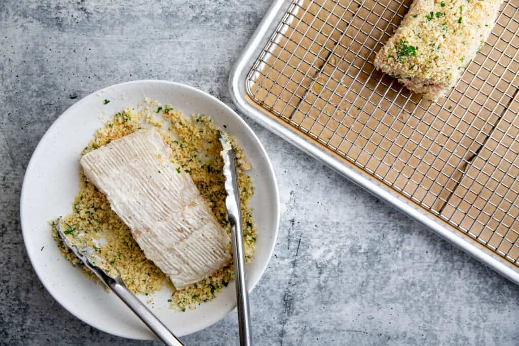 dipping a halibut filet into the breadcrumb mixture.