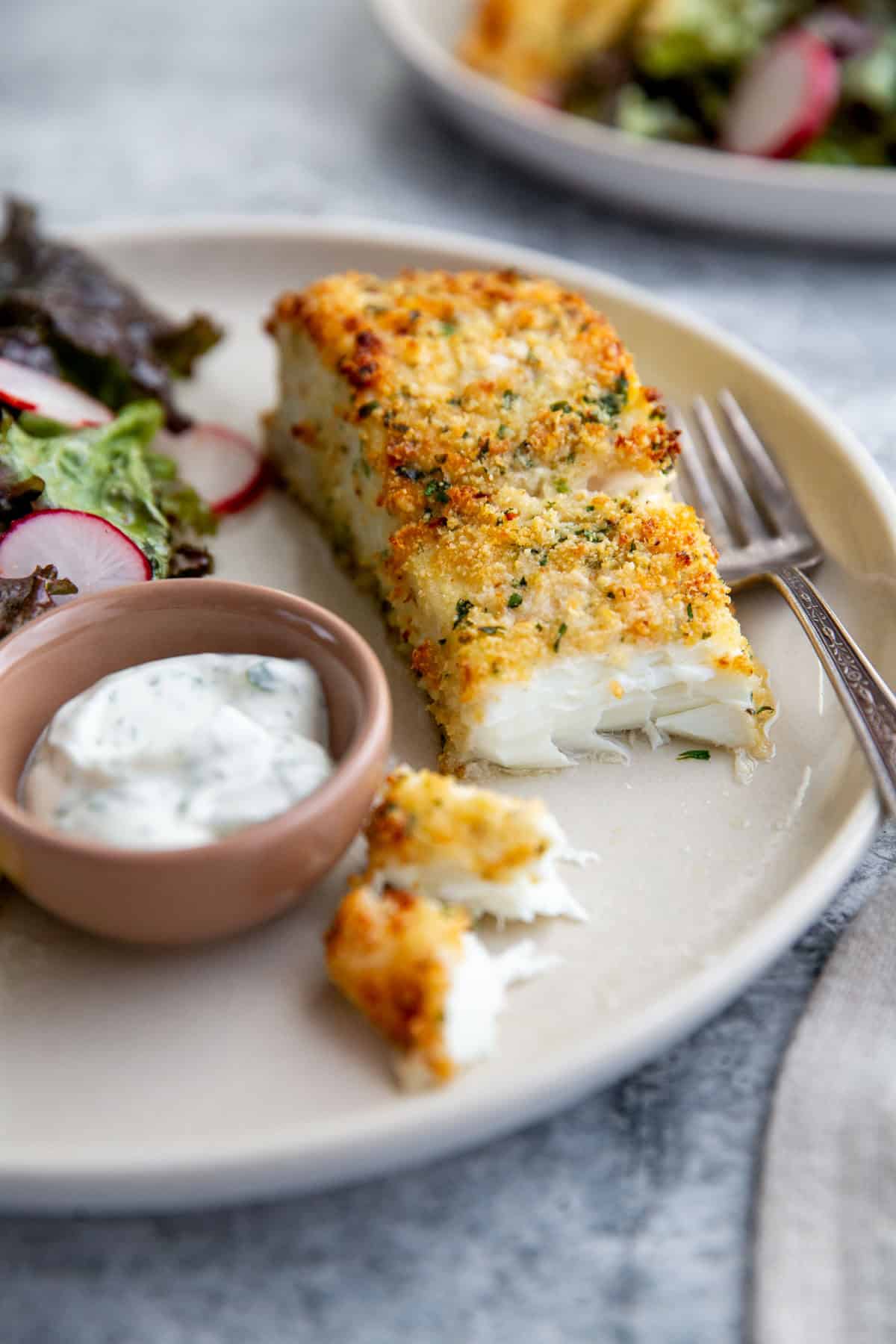 parmesan crusted halibut filet with two bites taken out to show the flakey center.