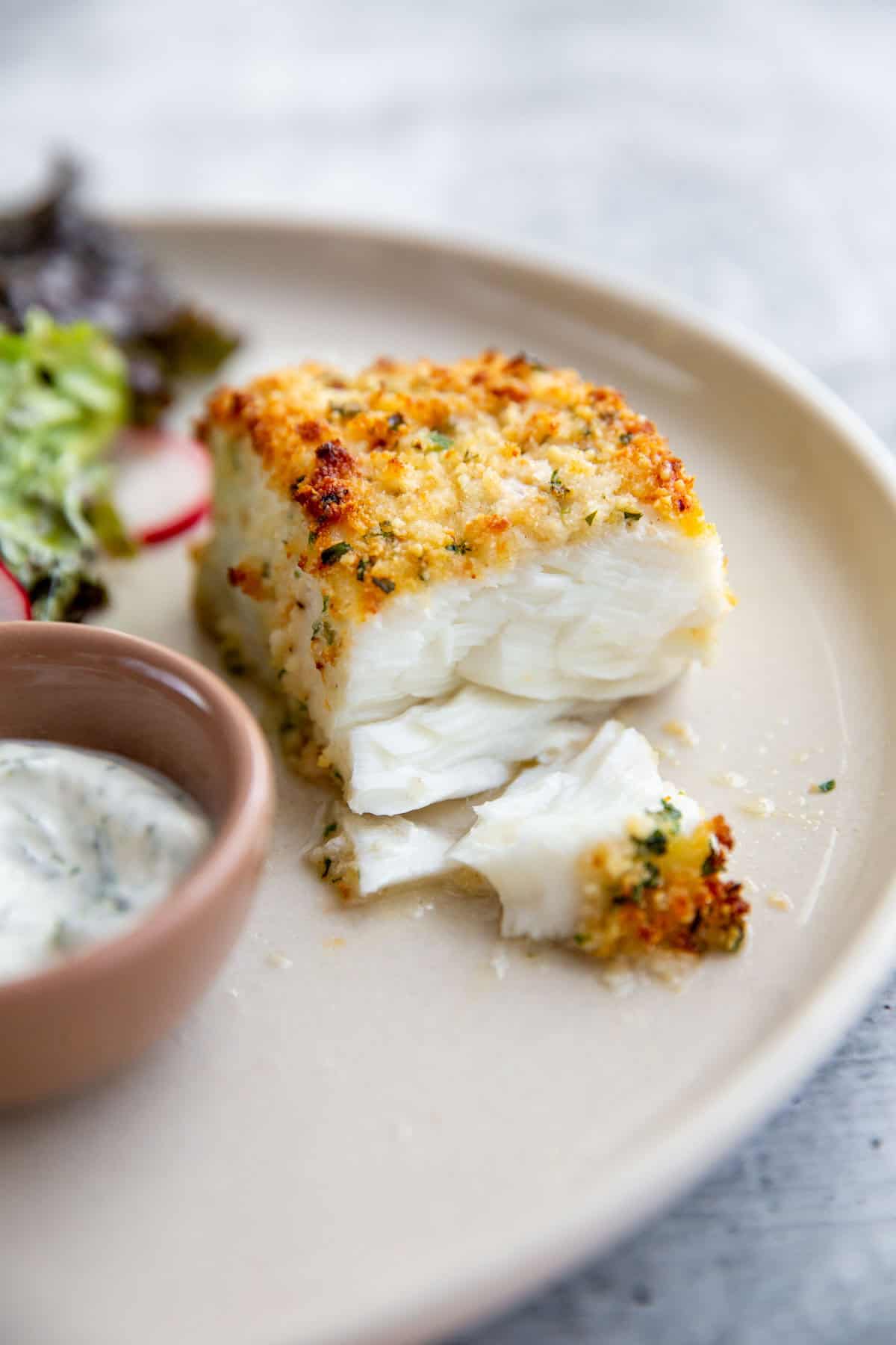 half of a parmesan crusted halibut filet showing the flaky, tender center.