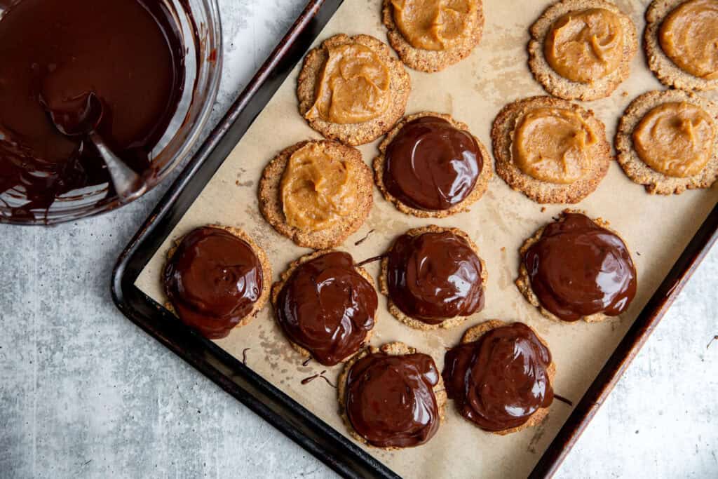 spooning carmel and chocolate onto the cookie base