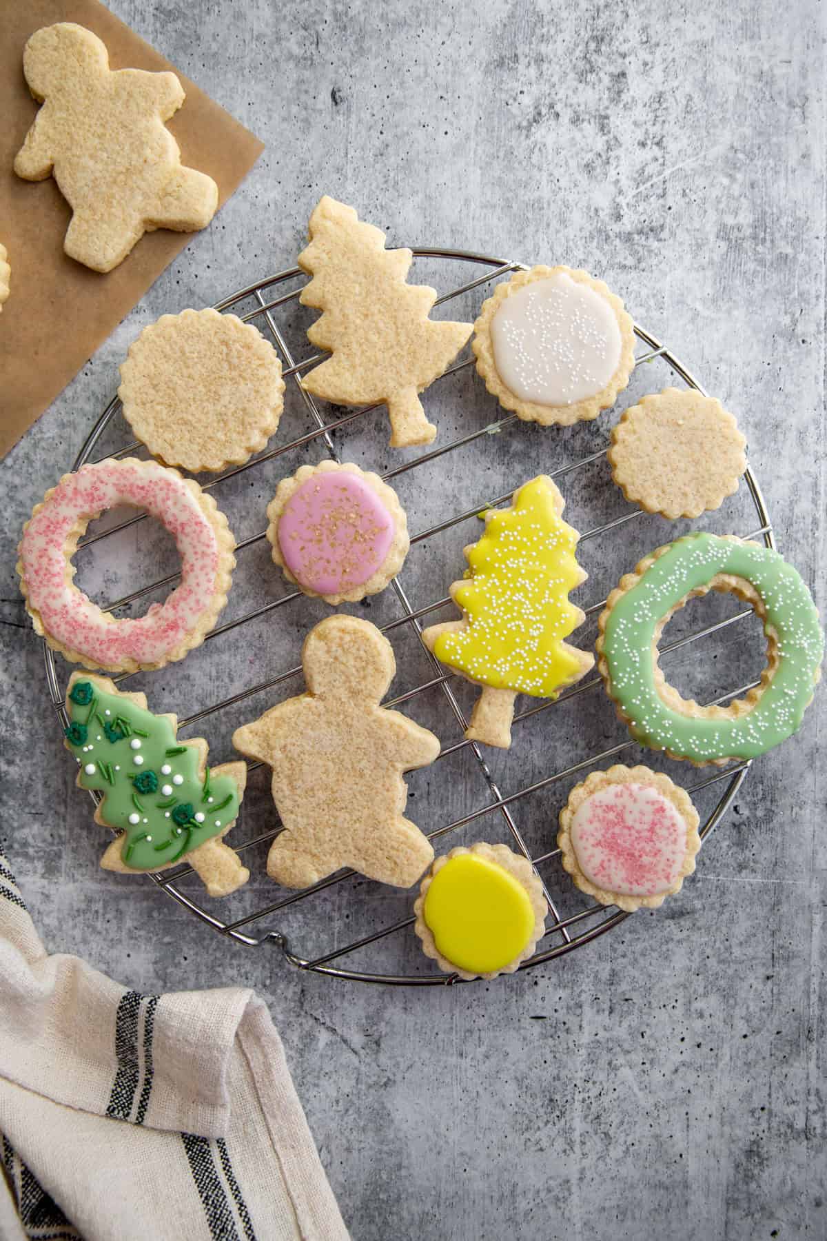 gluten free sugar cookies on a wire baking rack getting decorated with icing.