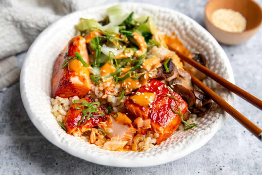 a bowl built with salmon, veggies, cucumbers, and sauce