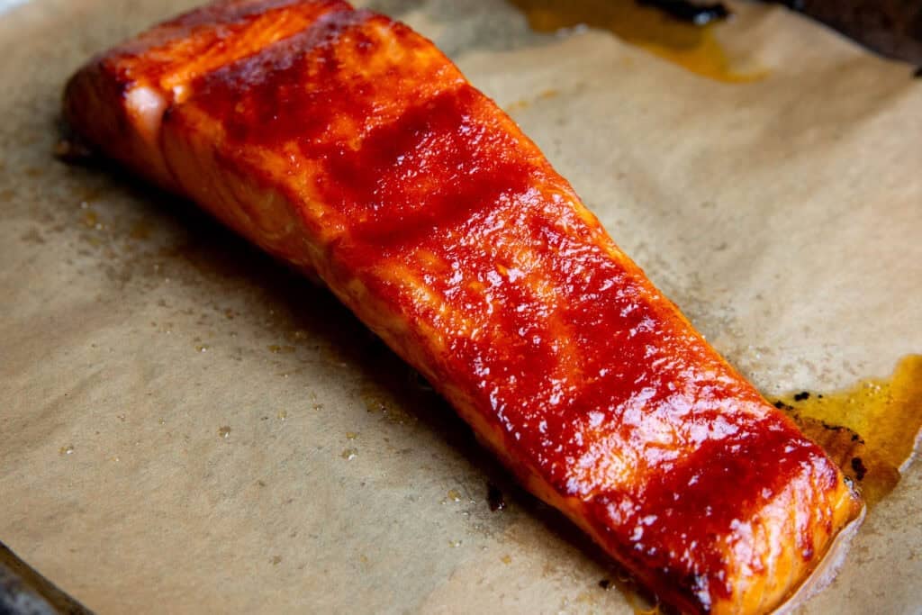 a glazed piece of gochujang salmon on a baking sheet lined with parchment paper