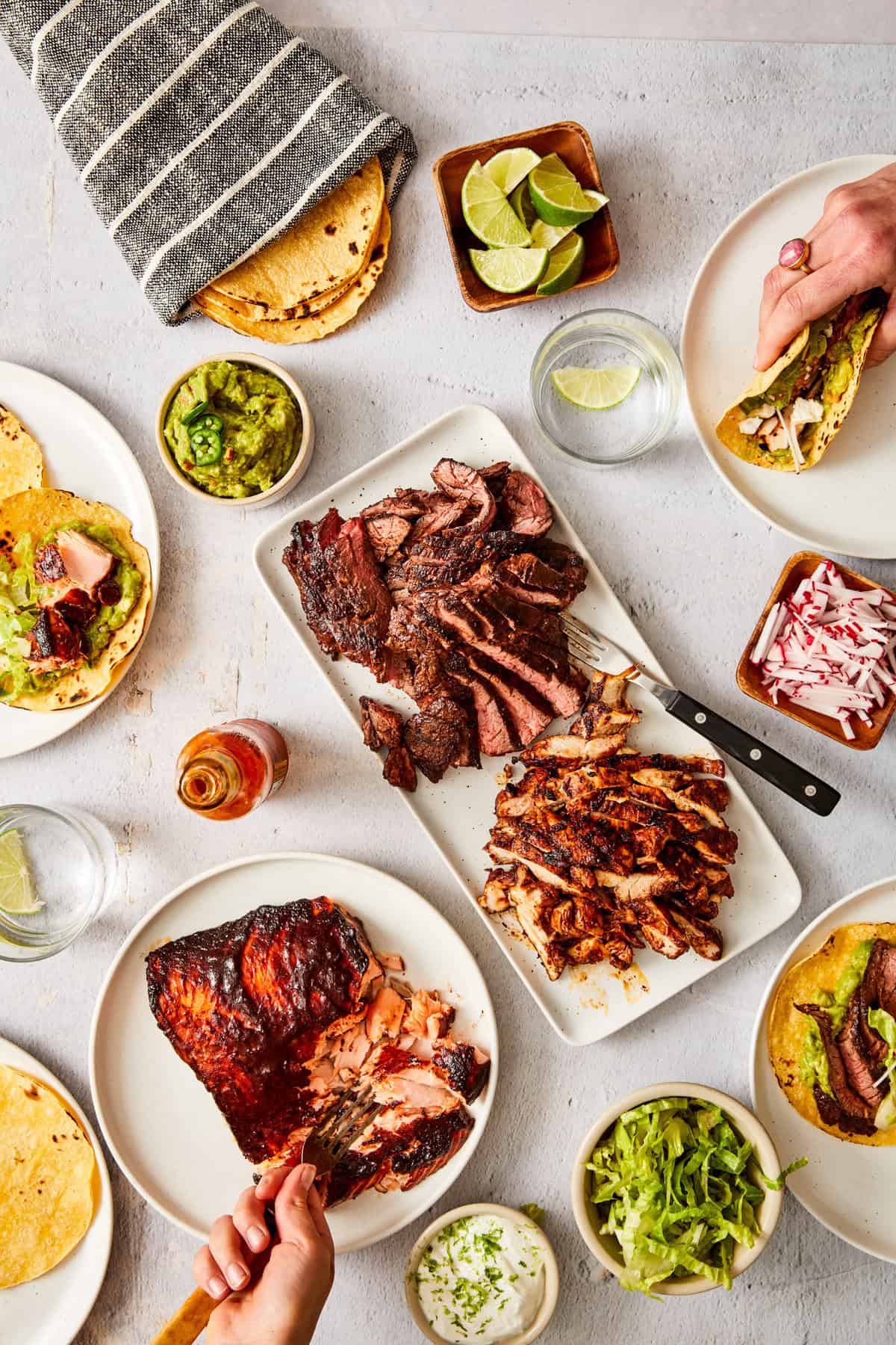 a collection of plates filled with steak, and ingredients to build tacos. 