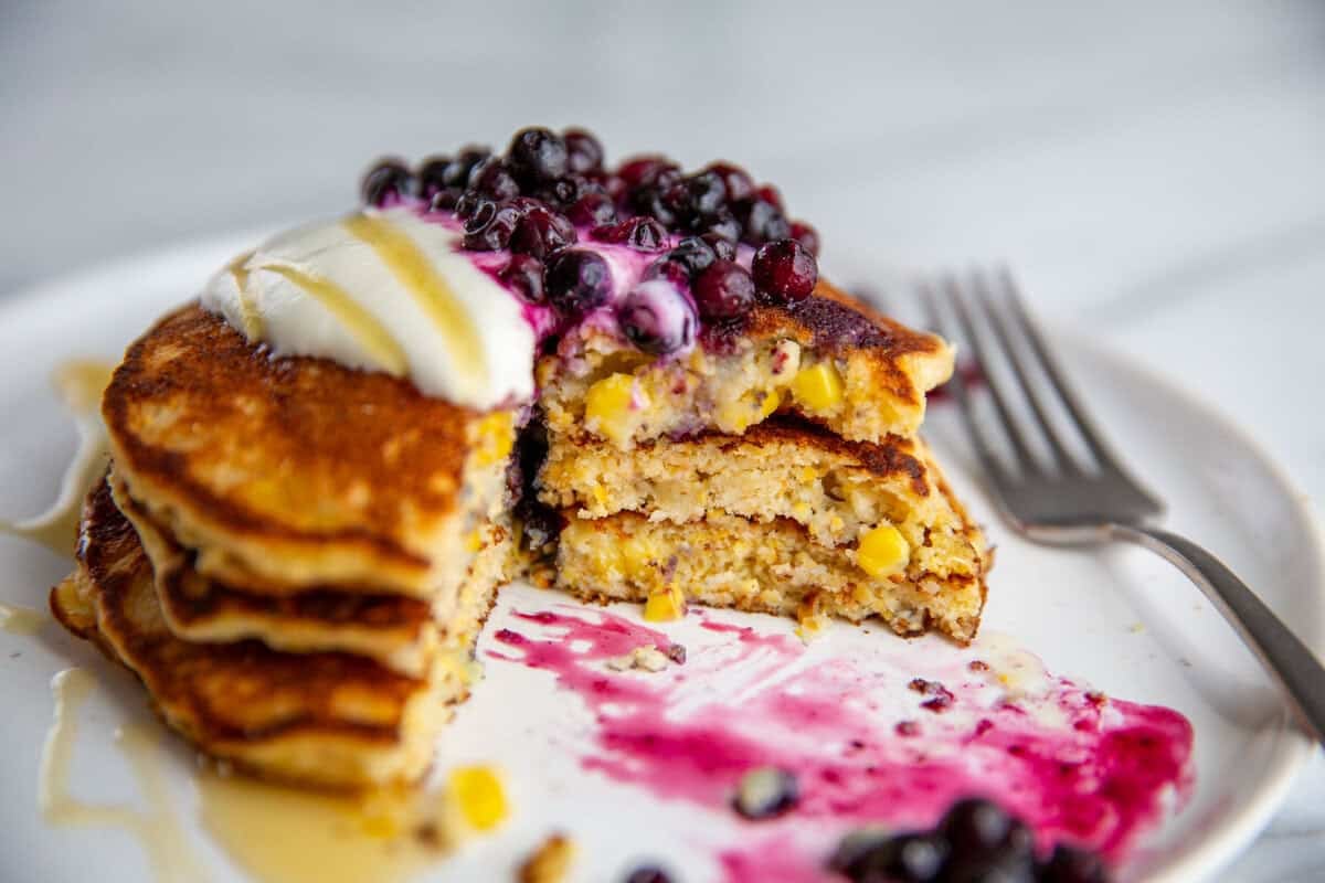 a stack of of sweet corn cakes cut and topped with blueberries.