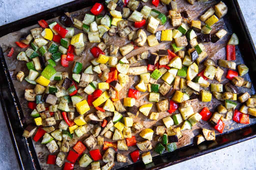 Roasted, diced veggies on a sheet pan after baking in the oven.