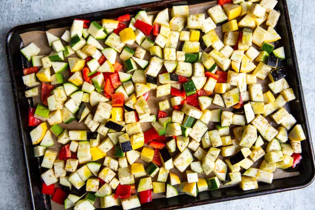 Diced, raw veggies on a sheet pan before roasting.