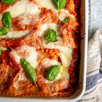 Gluten-free vegetable lasagna topped with basil sprigs in a white casserole dish.
