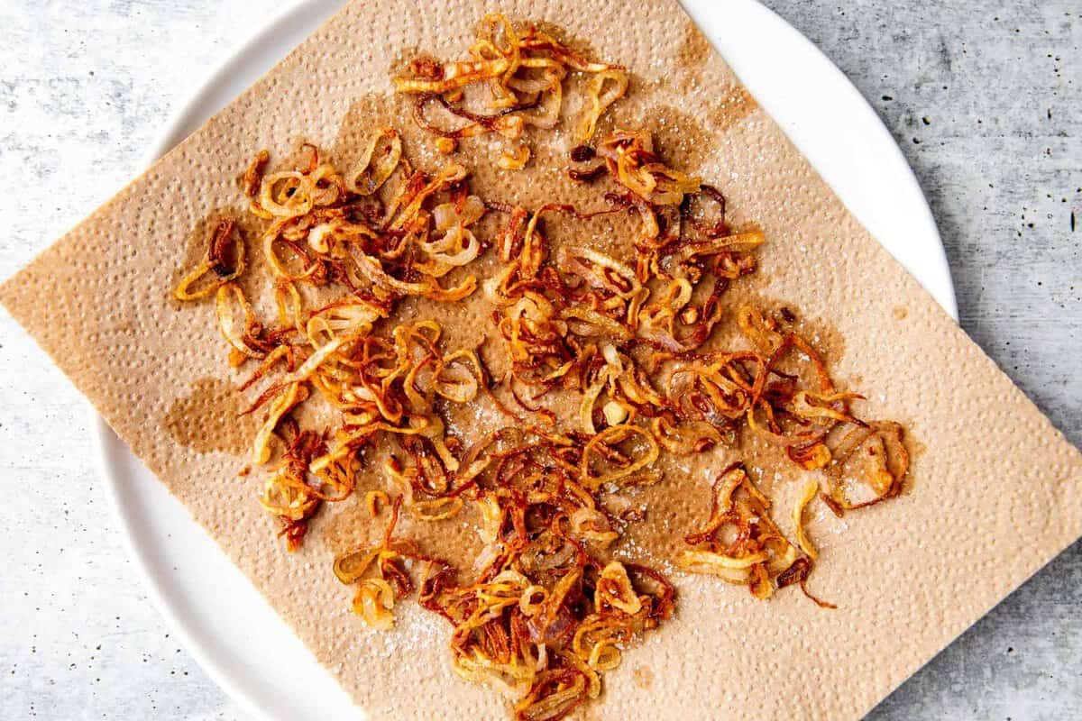 crispy fried shallots on a plate with a paper towel to drain the oil.