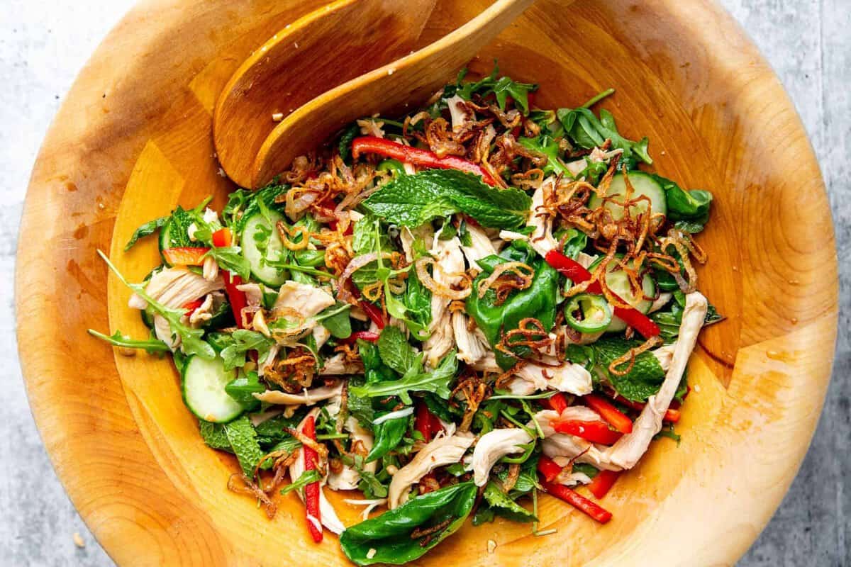 Vietnamese chicken salad ingredients in a wooden salad bowl combined with crispy shallots.