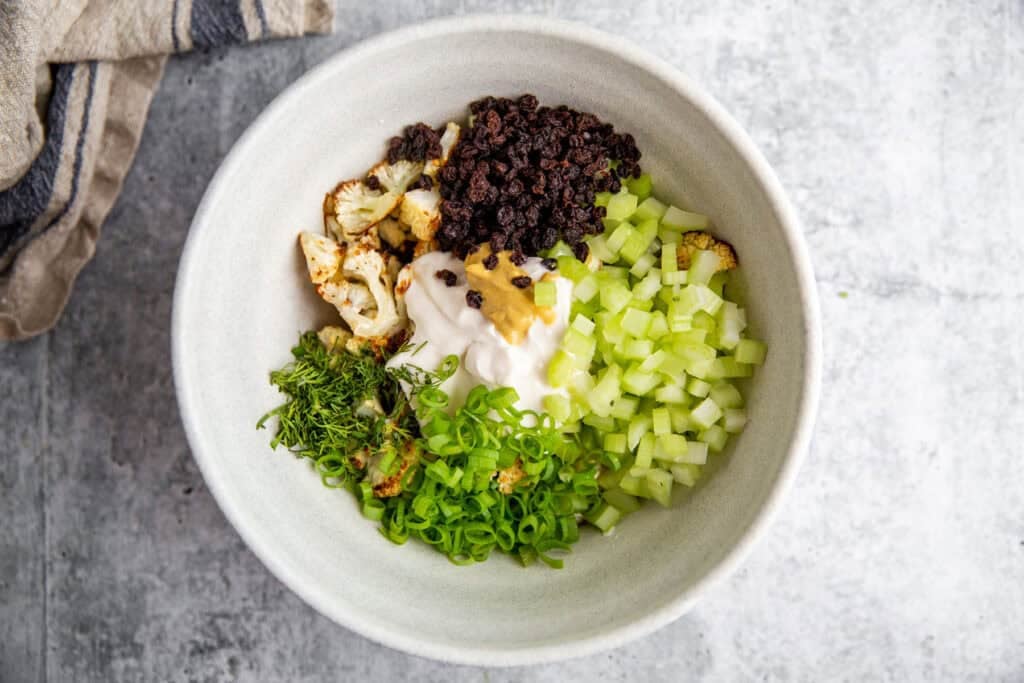 all of the ingredients for the roasted cauliflower salad in a white bowl