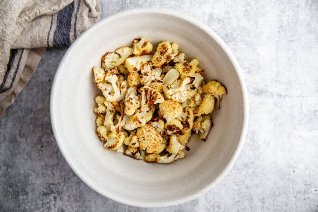 cauliflower chopped into small pieces in a white bowl