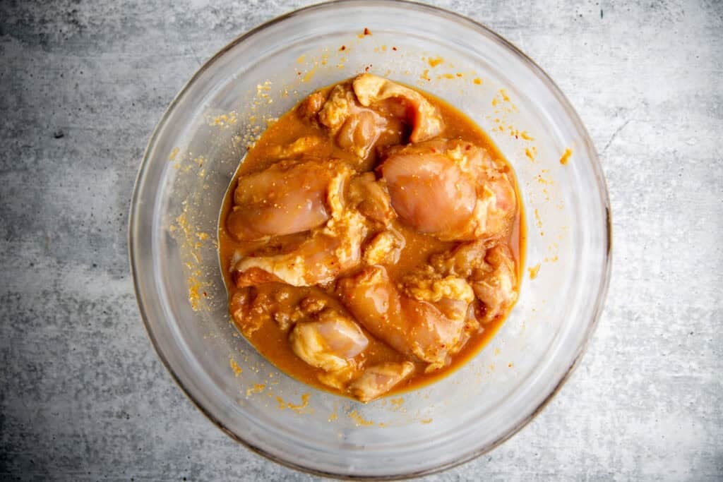 Chicken in a glass bowl with miso marinade.