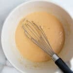 A bowl of miso dressing with a whisk resting on the side.