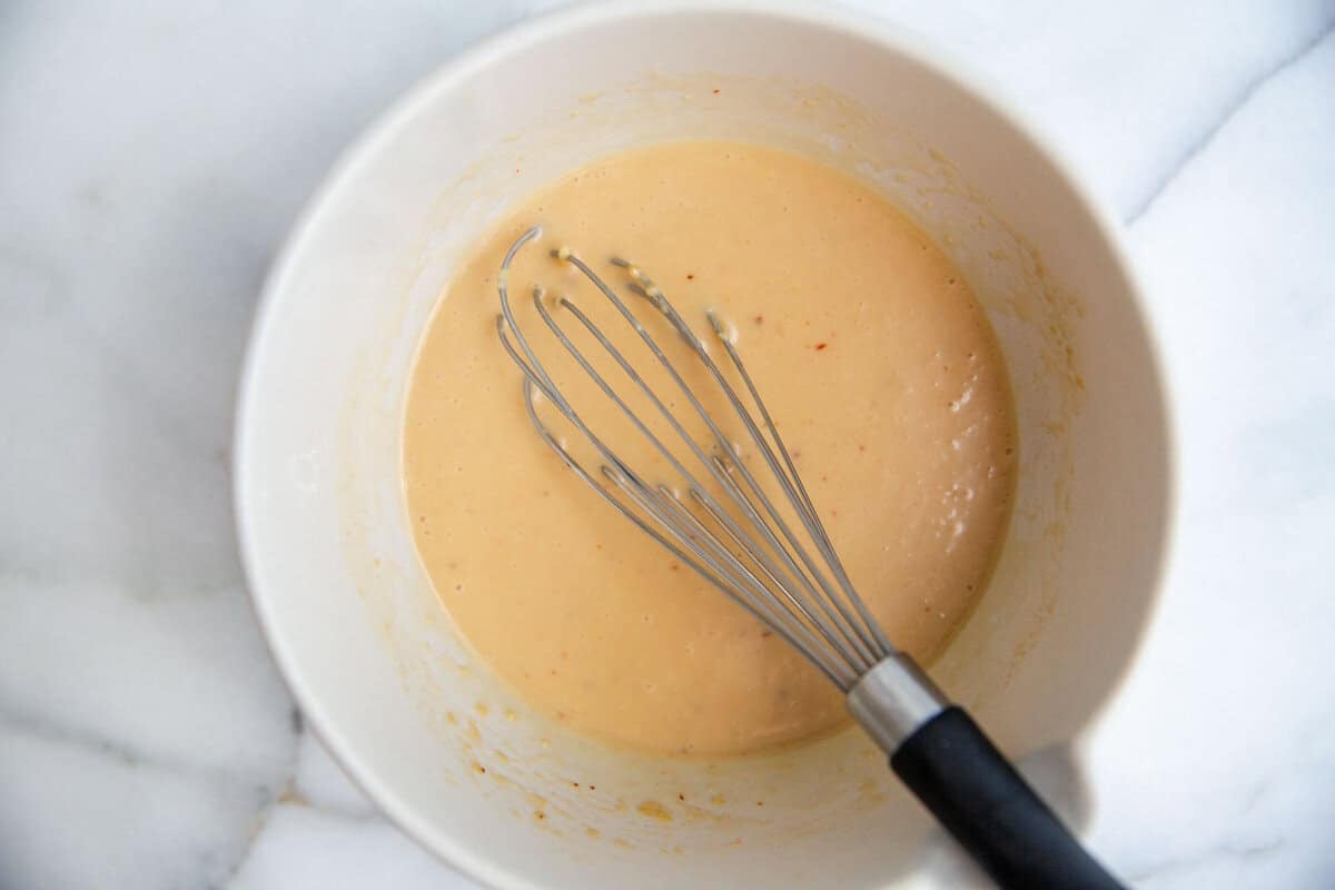 A bowl of miso dressing with a whisk resting on the side.