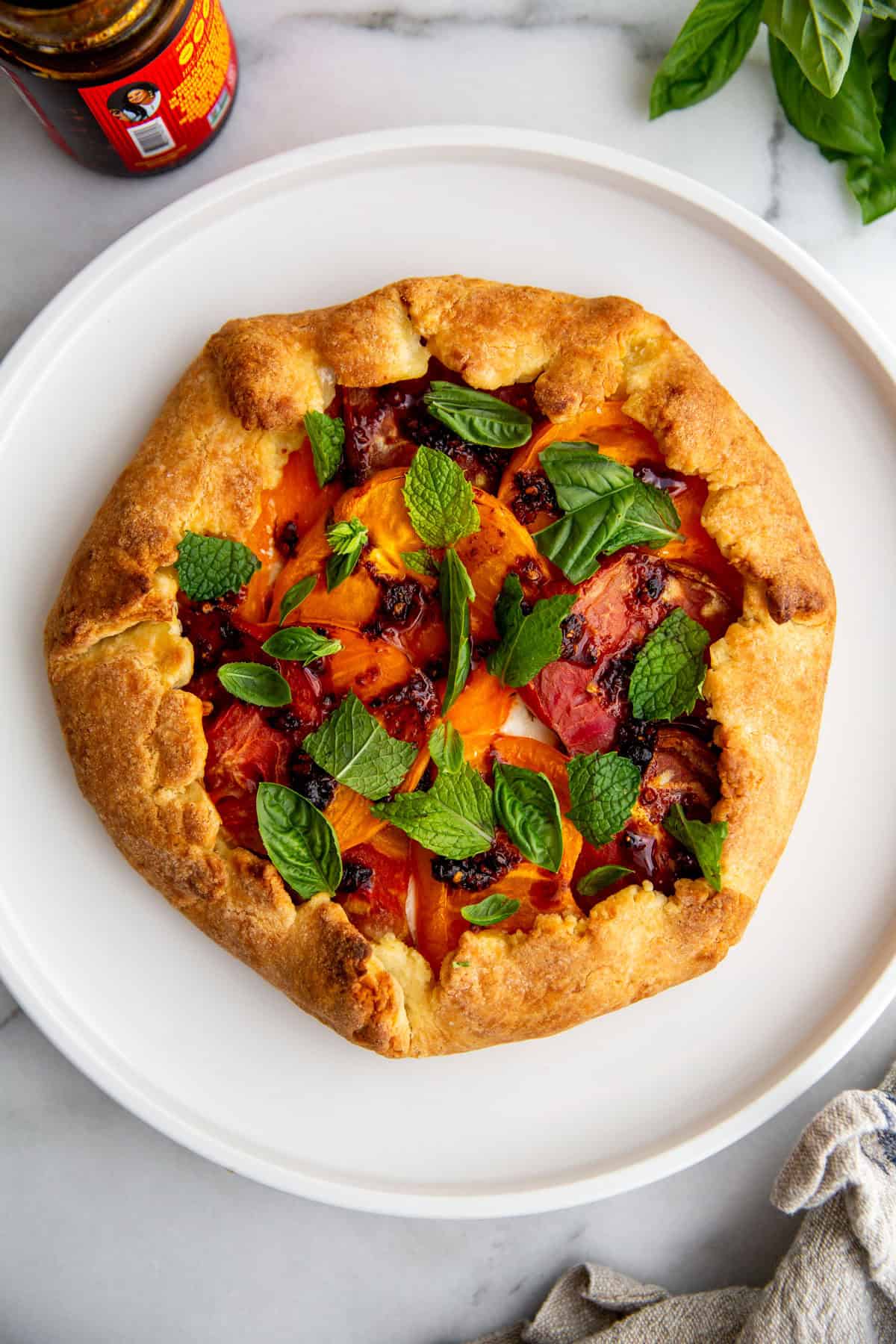 an overhead shot of a tomato galette topped with fresh mint on a white plate.